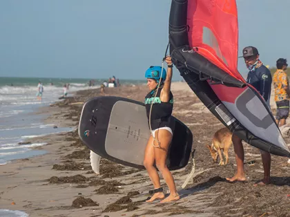 Beginner learning wing foil in Mayapo La Guajira with instructor using radio helmet